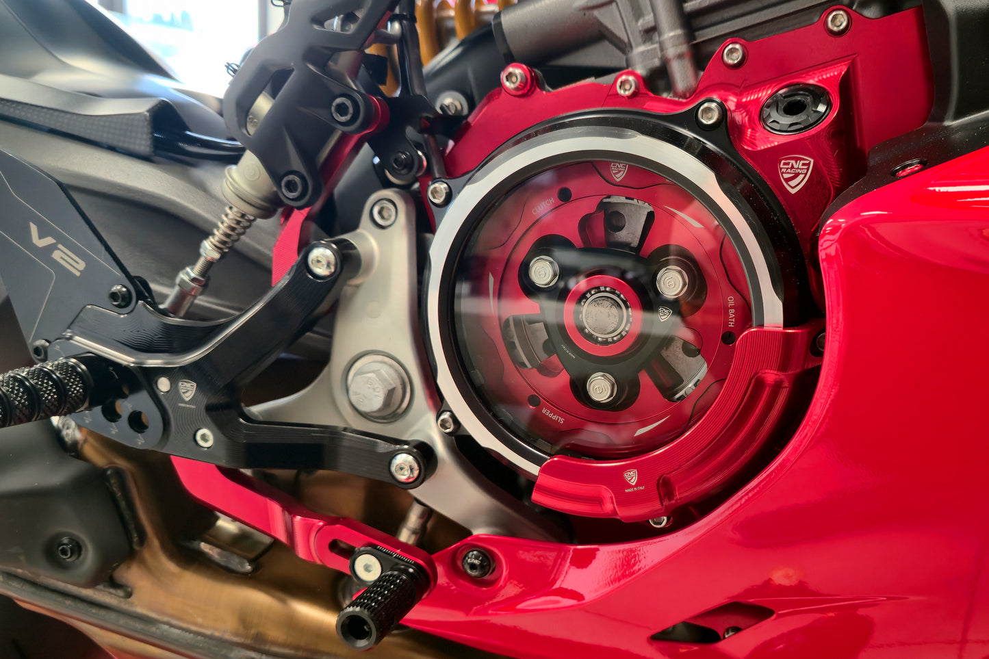 CNC Racing CA511RB transparant koppelingsdeksel met rode CAP03R beschermer – gemonteerd op Ducati 890cc V2, close-up van koppeling en frameconstructie.